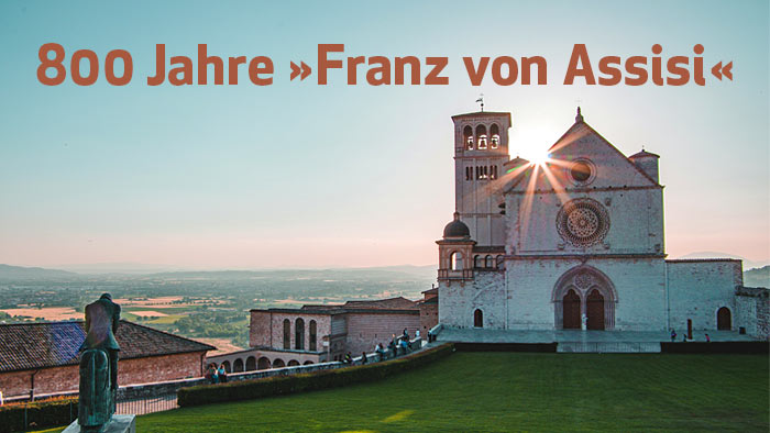 Hellbraune Schrift  800 Jahre »Franz von Assisi« - im Hintergrund Basilika San Francis von Assisi bei Sonnenuntergang