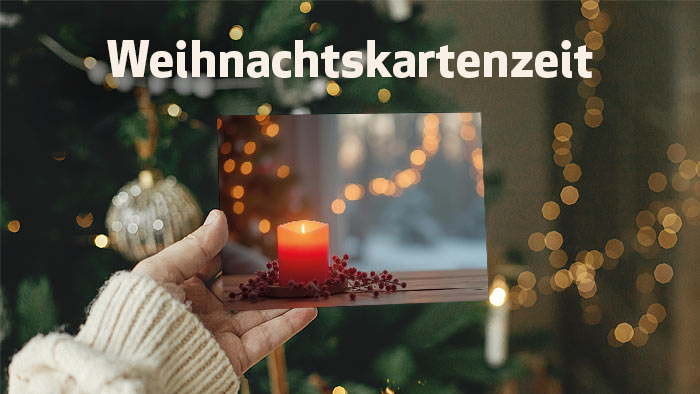 zur Themenseite Weihnachtskartenzeit weiße Schrift Weihnachtskartenzeit - im Hintergrund eine Frau, die eine Eschbacher weihnachtskarte zeigt